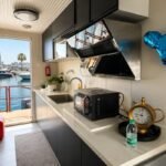 Modern floating houseboat featuring a spacious living room, private bedroom, kitchen, and outdoor seating area.